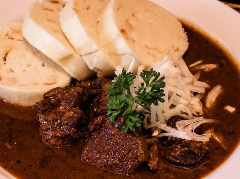 Masová specialita s omáčkou a knedlíky v restauraci U Bedřicha